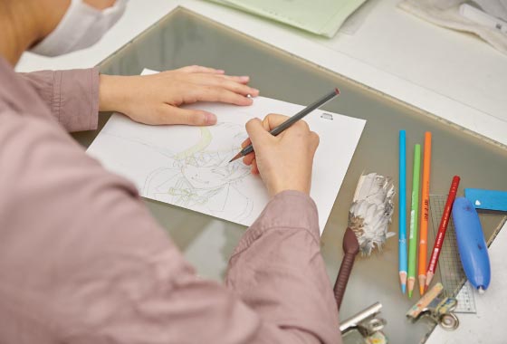▲ 原画を描く伊東さん。デジタルよりも鉛筆で描いた線の方が味があって好きだと話す。